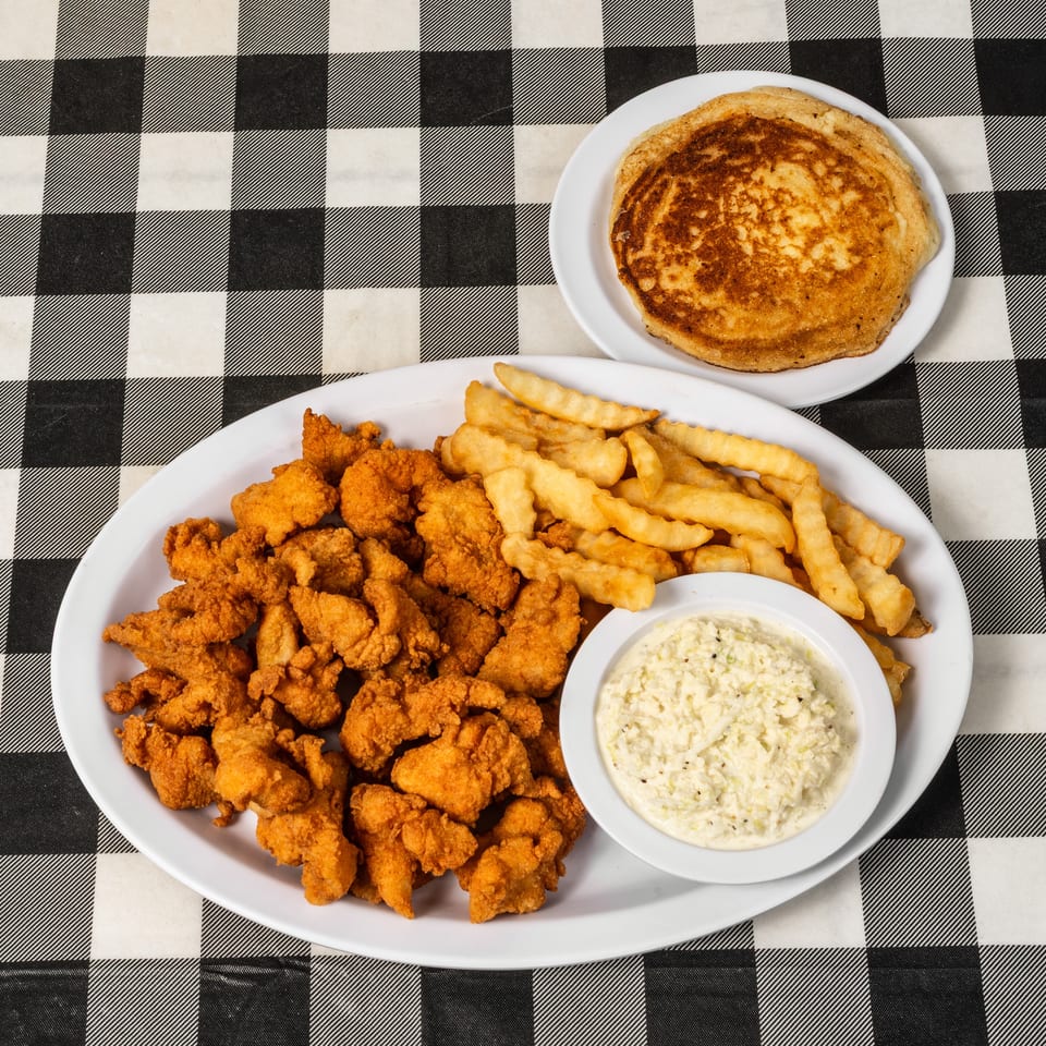 Fried chicken, french fries, coleslaw, and a pancake on a black and white checkered tablecloth.